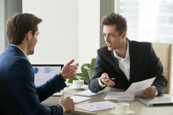 Two successful businessmen discussing company financial strategy, analyzing economic indicators, planning profitability and stock value growth while sitting at desk in office during business meeting