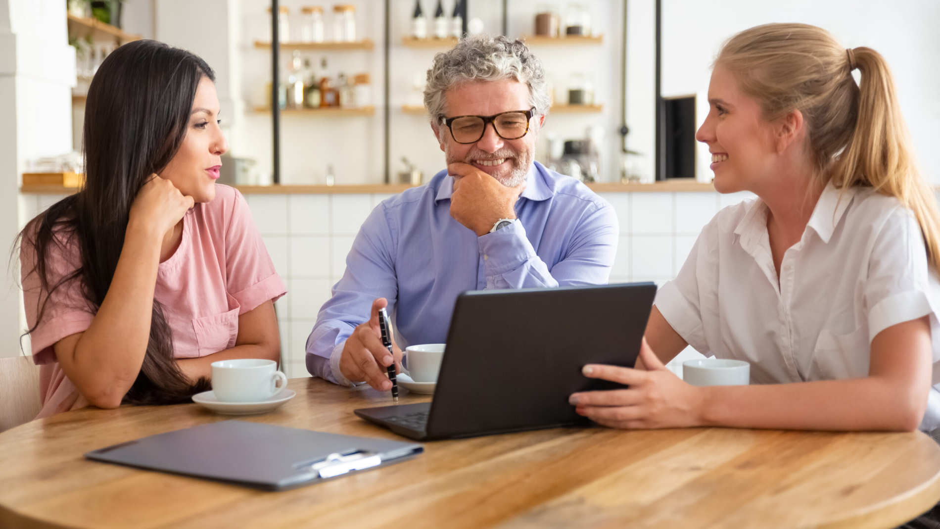 Happy female manager presenting project on laptop to young woman and mature man, discussing content with satisfied customers. Consulting or communication concept